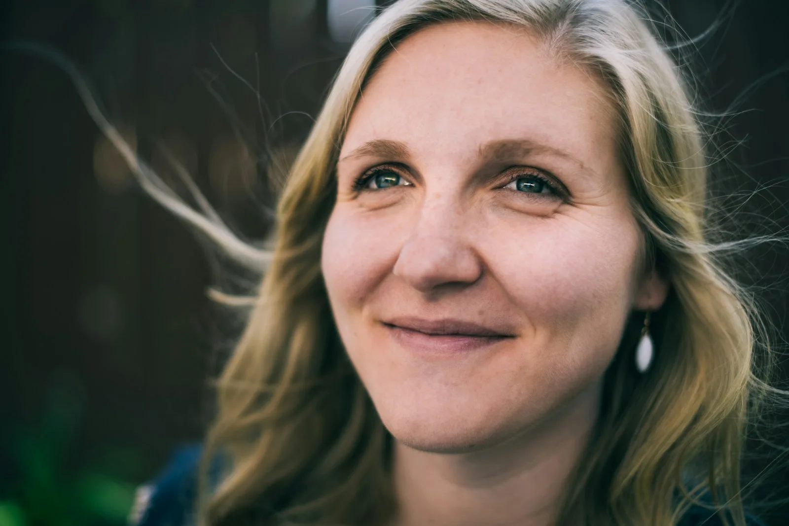 Frau mit blondem Haar lächelt sanft in die Kamera, Nahaufnahme