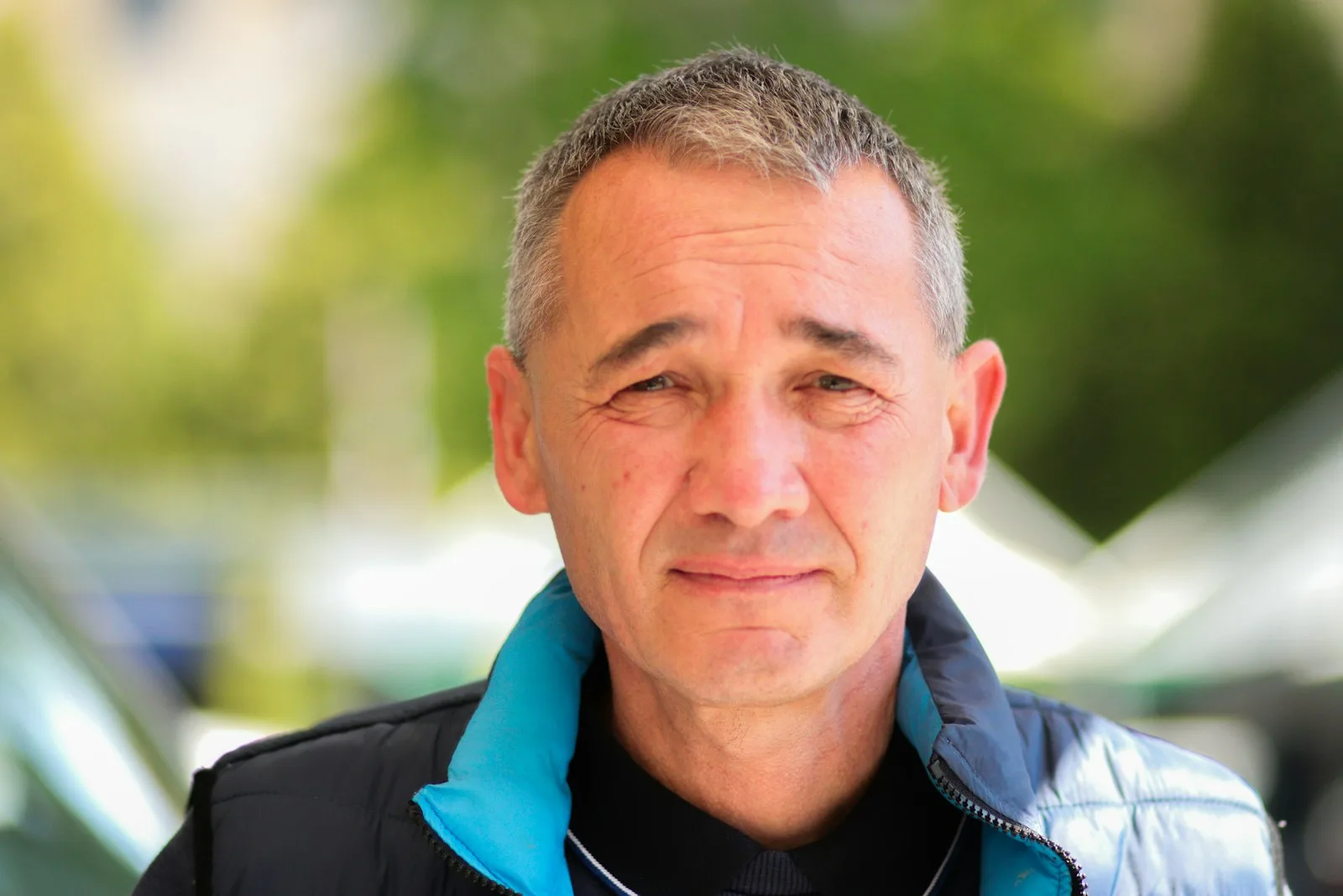 Mann mit kurzem grauem Haar lächelt, grüner Hintergrund