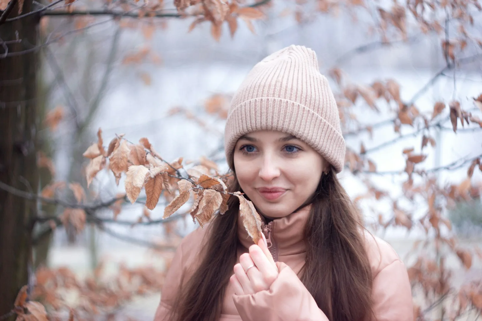 Frau mit rosafarbener Strickmütze zwischen Herbstzweigen