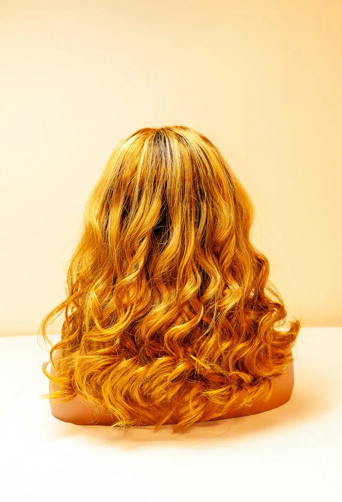 Gewellte goldblonde Perücke auf einem Ständer, von hinten
